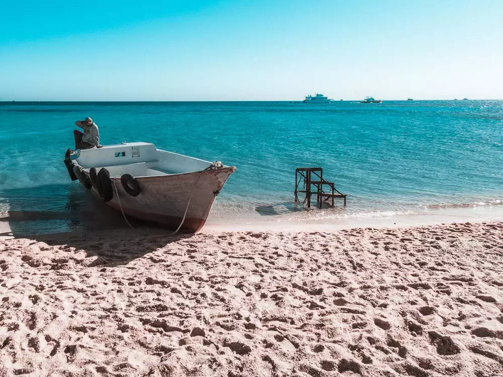 Boot liegt am Sandstrand von Giftun Island mit dem türkisblauen Meer im Hintergrund