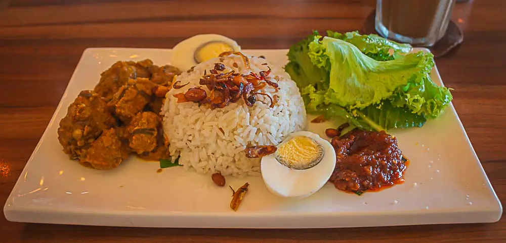 Nationalgericht von Malaysia, Nasi Lemak mit Reis, Eisern, Fleisch, Salat, Samabl Olek und Erdnüssen in einem Restaurant in Kuala Lumpur